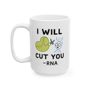 May include: White ceramic mug with the text "I WILL CUT YOU -RNA". The mug features a cartoon illustration of a green cell with scissors and a scared DNA strand.