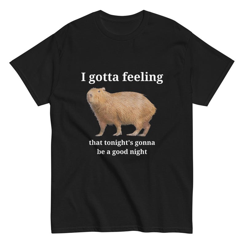 Pu&ograve; includere: Maglietta nera con testo bianco che recita "I gotta feeling that tonight's gonna be a good night". Un capibara marrone e bianco &egrave; raffigurato sotto il testo.
