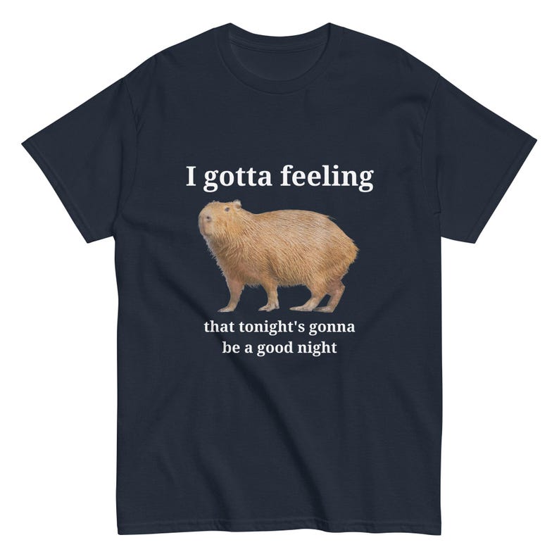 Pu&ograve; includere: Una t-shirt blu navy con un'illustrazione di capibara bianca e il testo "I gotta feeling that tonight's gonna be a good night".
