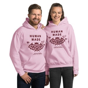 Pu&ograve; includere: Due felpe con cappuccio rosa con una grafica di pipistrello bordeaux e il testo "Human Made" e "Uzi Vert" sul davanti. Il testo sotto la grafica del pipistrello recita "Bridge Between Human and Infrahuman".