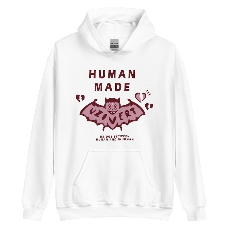 Pu&ograve; includere: Felpa con cappuccio bianca con una grafica di pipistrello rosso e il testo "HUMAN MADE" e "UZOVERT" con simboli di cuori spezzati. Il testo sotto la grafica dice "BRIDGE BETWEEN HUMAN AND INHUMAN".