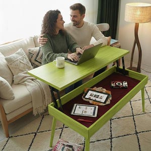 Puede incluir: Una mesa de centro elevable de color verde lima con un compartimento inferior. La mesa tiene una tapa rectangular y cuatro patas. El compartimento inferior está forrado con una tela burdeos y contiene dos tabletas y un libro pequeño. Una pareja está sentada en la mesa.