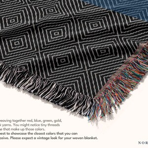 May include: Woven blanket with a geometric diamond pattern in black and white. The blanket has a fringed edge with red, blue, green, and gold threads. The text on the image says, "Crafted by weaving together red, blue, green, gold, white & black yarns."