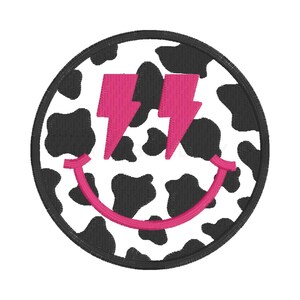 May include: A black and white cow print smiley face with pink lightning bolts.