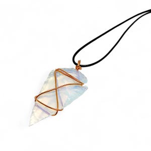 Könnte beinhalten: Ein weißer Opal-Pfeilspitzenanhänger, der mit Kupferdraht umwickelt ist und an einer schwarzen Schnurkette hängt.