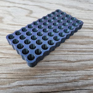 May include: A black and blue plastic tray with a honeycomb pattern and 48 round indentations.
