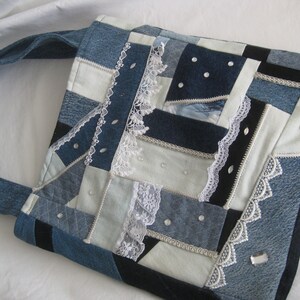 May include: A patchwork tote bag made from denim fabric with white lace trim and white buttons. The bag has a long denim strap.