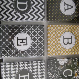 May include: A collection of personalized stationery featuring various patterns and initial letters. Designs include chevron, polka dots, floral, and houndstooth. Each card has a white initial in a gray circle.