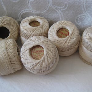 May include: Six balls of off-white mercerized cotton crochet thread. Each ball features a circular paper label in the center with red and gold text that reads Clark's Big Ball, Mercerized Boilfast, and the number 30 in a central circle.