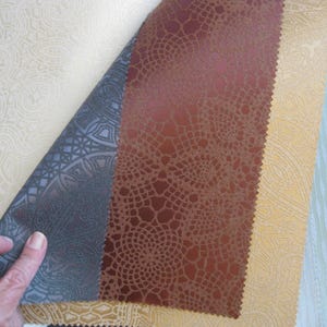 May include: Four fabric swatches with different patterns and textures. The swatches are arranged in a row, with the first swatch being a light beige with a subtle pattern, the second swatch is a dark gray with a geometric pattern, the third swatch is a brown with a textured pattern, and the fourth swatch is a light beige with a subtle pattern.