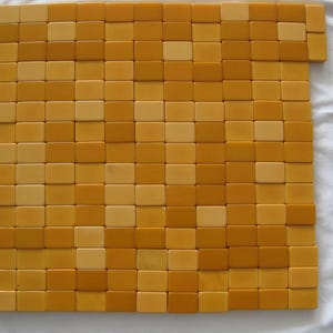 May include: A collection of rectangular tiles arranged in a grid pattern, featuring a mix of light yellow and deep mustard yellow colors. The tiles are laid out in a square formation with a few extra tiles extending from the top right corner.