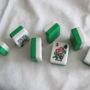 K&ouml;nnte beinhalten: Eine Ansammlung wei&szlig;er und gr&uuml;ner Mahjong-Steine. Die Steine haben gr&uuml;ne Kanten und sind oben und an den Seiten wei&szlig;. Einige Steine zeigen Illustrationen und die Zahl "3". Die Steine liegen auf einer wei&szlig;en Oberfl&auml;che.