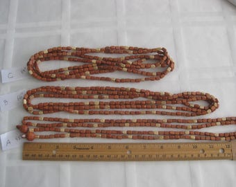 May include: Three strands of wooden beads, each with a different length. The beads are a mix of brown and gold colors. The strands are labeled A, B, and C with their corresponding lengths in inches. A ruler is visible at the bottom of the image.
