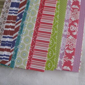 May include: A collection of patterned paper strips in various colors, including green, red, blue, and purple. The strips have different patterns, such as stripes, polka dots, and floral designs.