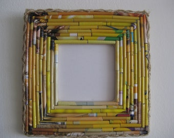May include: A yellow and brown picture frame made from rolled up magazine paper and twine. The frame has a rectangular shape and is ready to hold a photo or artwork.
