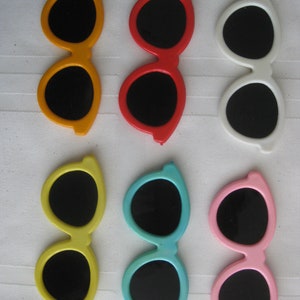 May include: Six pairs of plastic sunglasses in various colors, including yellow, red, white, blue, and pink. Each pair has black lenses.