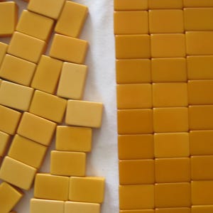 May include: A collection of rectangular mustard-yellow mahjong tiles. On the left, the tiles are scattered in an irregular, overlapping arrangement. On the right, the tiles are organized into a neat, uniform grid of rows and columns.