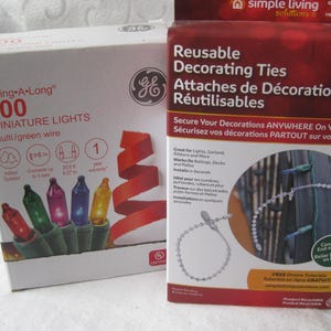 May include: A white box of 100 String-A-Long miniature multi-colored lights with green wire and a maroon box of 20 reusable decorating ties. The light box shows red, green, purple, blue, and yellow bulbs. The tie box shows clear plastic ties.