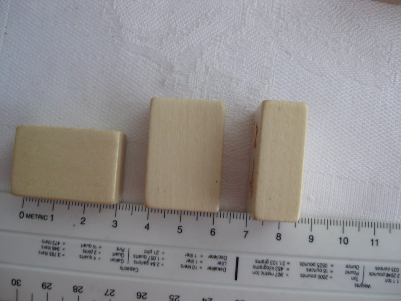 May include: Three rectangular wooden blocks, each with a different size. The blocks are light brown in color and are arranged in a row from smallest to largest.