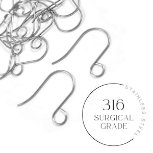 May include: A close-up of a pile of silver earring hooks. The hooks are made of surgical grade stainless steel, as indicated by the text "316 Surgical Grade Steel".