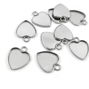 Peut inclure: Un groupe de plateaux pendentifs en forme de cœur argentés avec une boucle en haut pour accrocher. Les plateaux sont conçus pour contenir de petits objets, tels que de la résine, du verre ou d'autres matériaux.