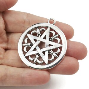 May include: Silver pendant featuring a five-pointed star within a circular design. The star is encircled by a decorative border of fleur-de-lis.