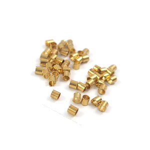 Peut inclure: Un tas de perles à sertir en métal couleur or, utilisées pour la fabrication de bijoux.