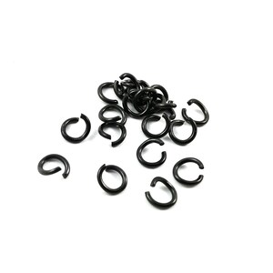 May include: A pile of black metal jump rings, scattered on a white background. These rings are used for jewellery making and crafting.