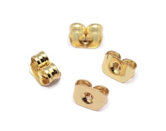 May include: Four gold-colored earring backs. The backs are designed to secure earrings to the earlobe.