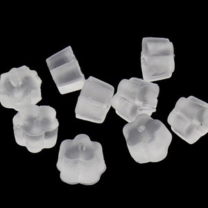 May include: A group of ten clear plastic earring backs. The backs are shaped like a flower with five petals.