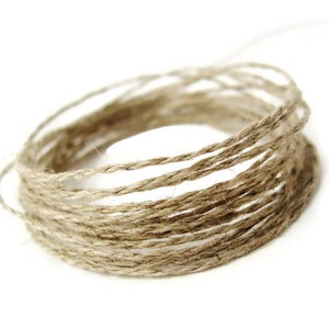 May include: A close-up of a coil of natural twine, a type of string made from natural fibres, often used for crafts and packaging.