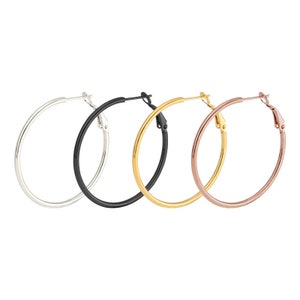 May include: Three pairs of hoop earrings in silver, black, and rose gold.