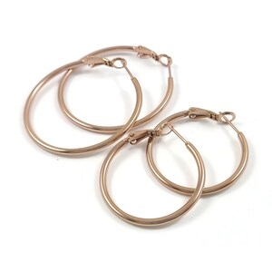 Peut inclure: Trois paires de créoles en or rose de différentes tailles. Les boucles d'oreilles sont en métal et ont un design simple et classique.