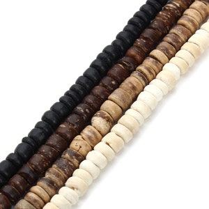 May include: A strand of wooden beads in four colours: black, dark brown, light brown, and white. The beads are round and have a slightly textured surface.