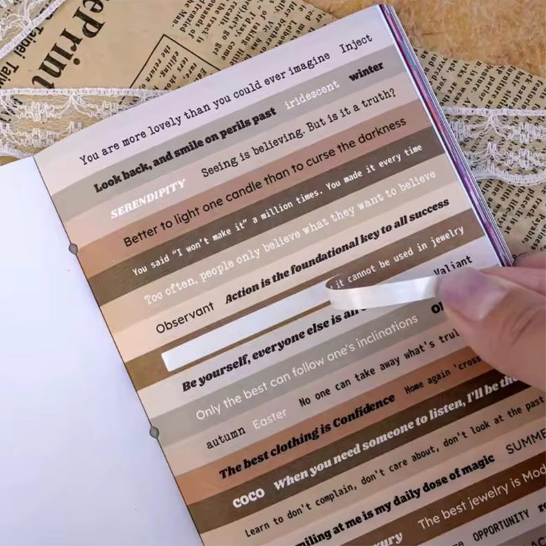 May include: Open notebook with inspirational quotes in various fonts and colors. The pages feature horizontal stripes with phrases like "Look back, and smile on perils past" and "Action is the foundational key to all success."