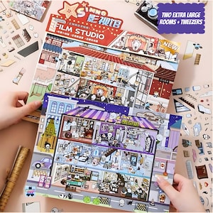 May include: Two colorful sticker books with scenes of a film studio and a spooky store. Each book includes stickers to decorate the scenes. The books are titled "SIMNO Film Studio" and "SIMNO Spooky Store".