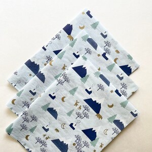 May include: Three sheets of white tissue paper with a blue and gold mountain and forest design. The design features mountains, trees, bears, deer, and moons.