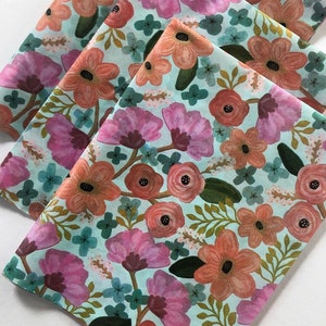 May include: A stack of three blue and white floral patterned gift wrap sheets with pink, orange, and green flowers.