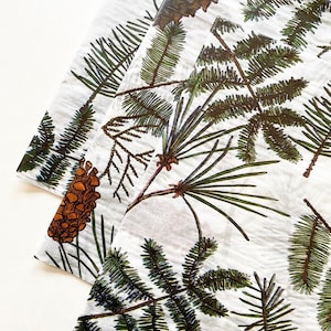 May include: White tissue paper with a repeating pattern of pine branches and pine cones. The pine branches are green and the pine cones are brown.