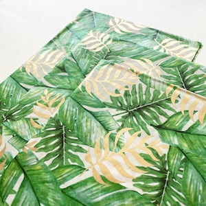 May include: A stack of three white tissue paper sheets with a tropical leaf pattern in shades of green and gold foil accents.