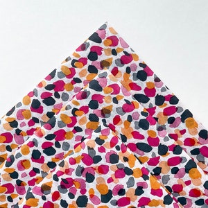 May include: A stack of three sheets of tissue paper with a pink, orange, and black abstract animal print pattern.