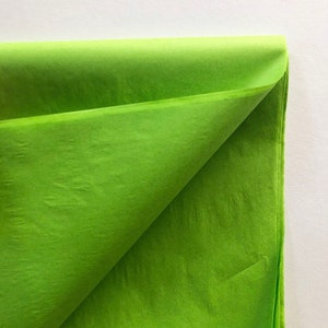 May include: A sheet of bright green tissue paper, folded in half, with a smooth, slightly textured surface.