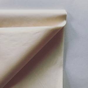 May include: A close-up of a folded piece of white fabric. The fabric is smooth and has a slight sheen.