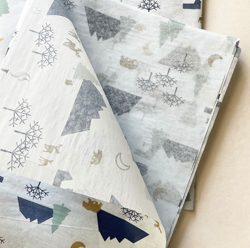 May include: White tissue paper with a repeating pattern of gray mountains, trees, and animals. The paper is folded in half, showing the pattern on both sides.