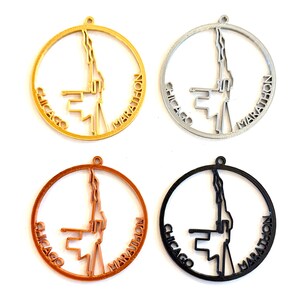 May include: Four Chicago Marathon pendant charms in gold, silver, copper, and black. Each charm features a circular design with the words "Chicago Marathon" and a stylized cityscape silhouette. The charms have a small loop at the top for hanging.