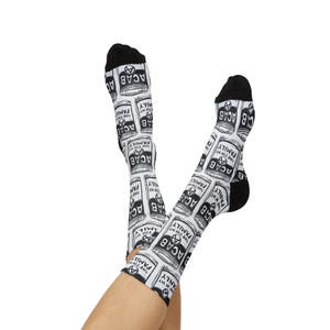 May include: White socks with black heels and toes, featuring a repeating pattern of ACAB text and a can design. The text "Soup for my Family" is also visible on the socks.