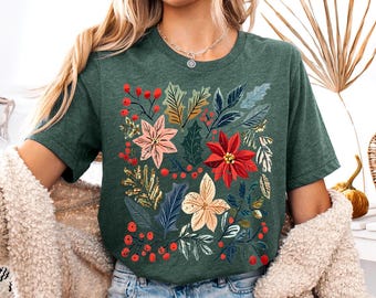 May include: A dark green short-sleeve t-shirt featuring a central graphic print of various botanical elements including red poinsettias, holly leaves, and small red berries arranged in a cluster across the front of the garment.