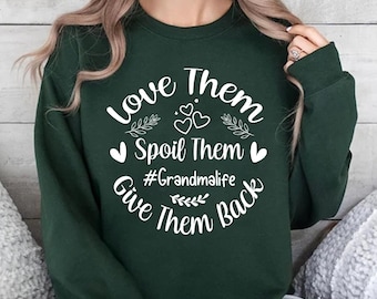 May include: A dark green long-sleeve sweatshirt featuring white text that reads Love Them Spoil Them #Grandmalife Give Them Back, accented with small heart and leaf illustrations arranged in a circular design on the front of the garment.