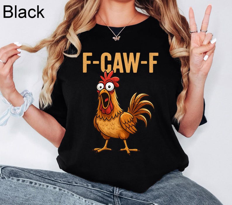 May include: A black short-sleeved t-shirt featuring a graphic of a wide-eyed, surprised-looking brown rooster with a red comb and wattle. Above the rooster, the text F-CAW-F is printed in a bold, light-colored, sans-serif font.