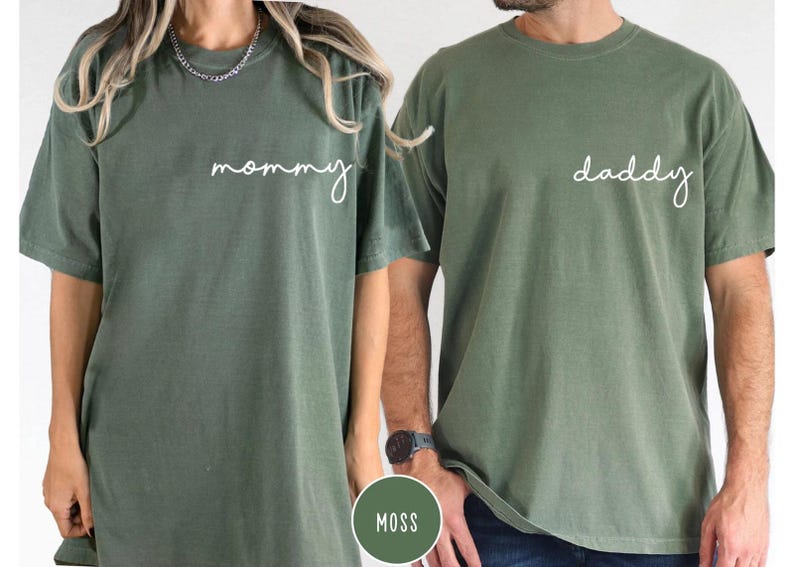 Pu&ograve; includere: Due magliette a maniche corte con girocollo in un colore verde muschio tenue. La maglietta a sinistra presenta la parola mommy in corsivo bianco sul petto, mentre quella a destra presenta la parola daddy in corsivo bianco sul petto.
